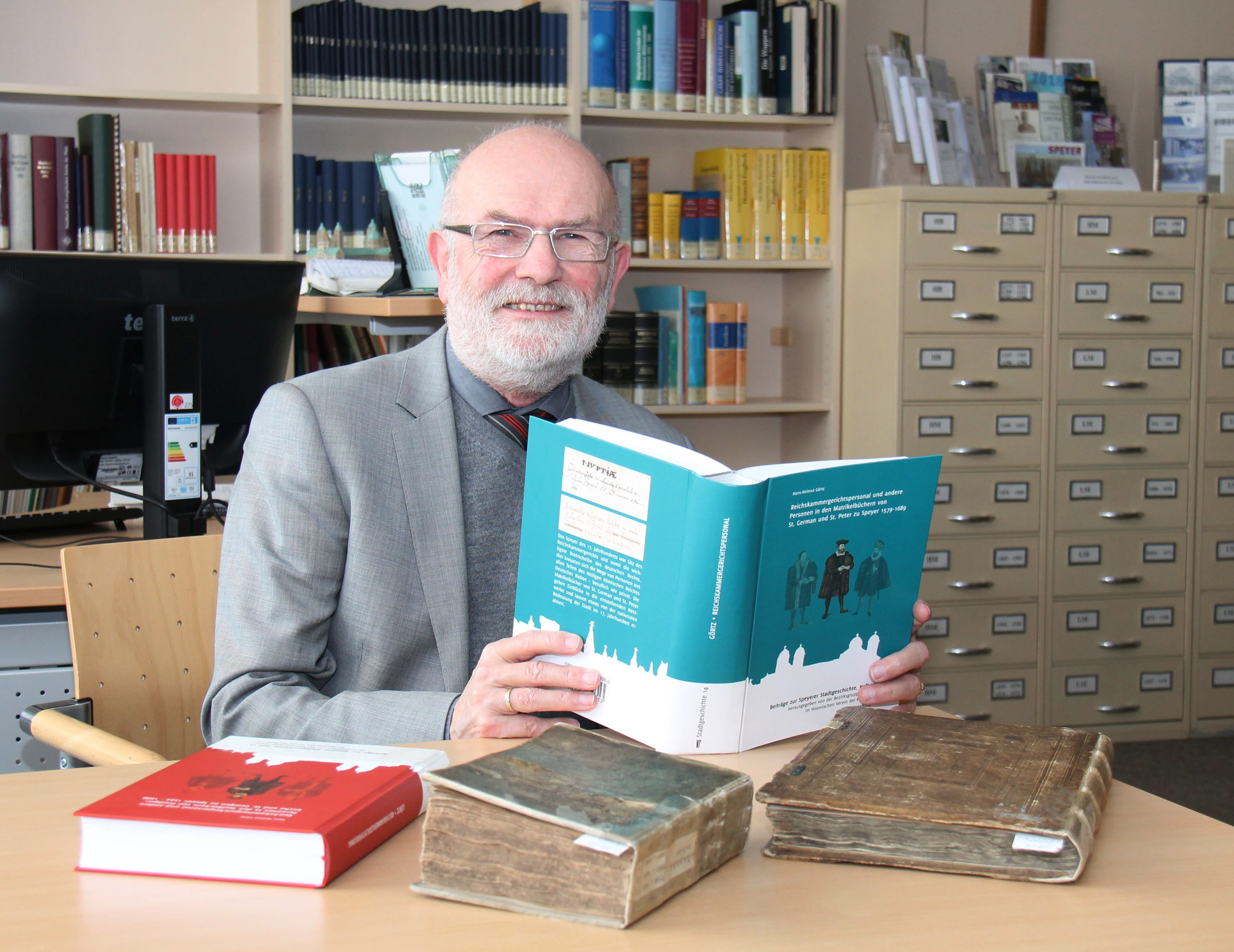 Autor Dr. Hans-Helmut Görtz bei der Präsentation seines Buches im Bistumsarchiv in Speyer. Auf dem Tisch die beiden Original-Kirchenbücher, die er für seine Studie ausgewertet hat, sowie sein Buch aus dem Jahr 2015.