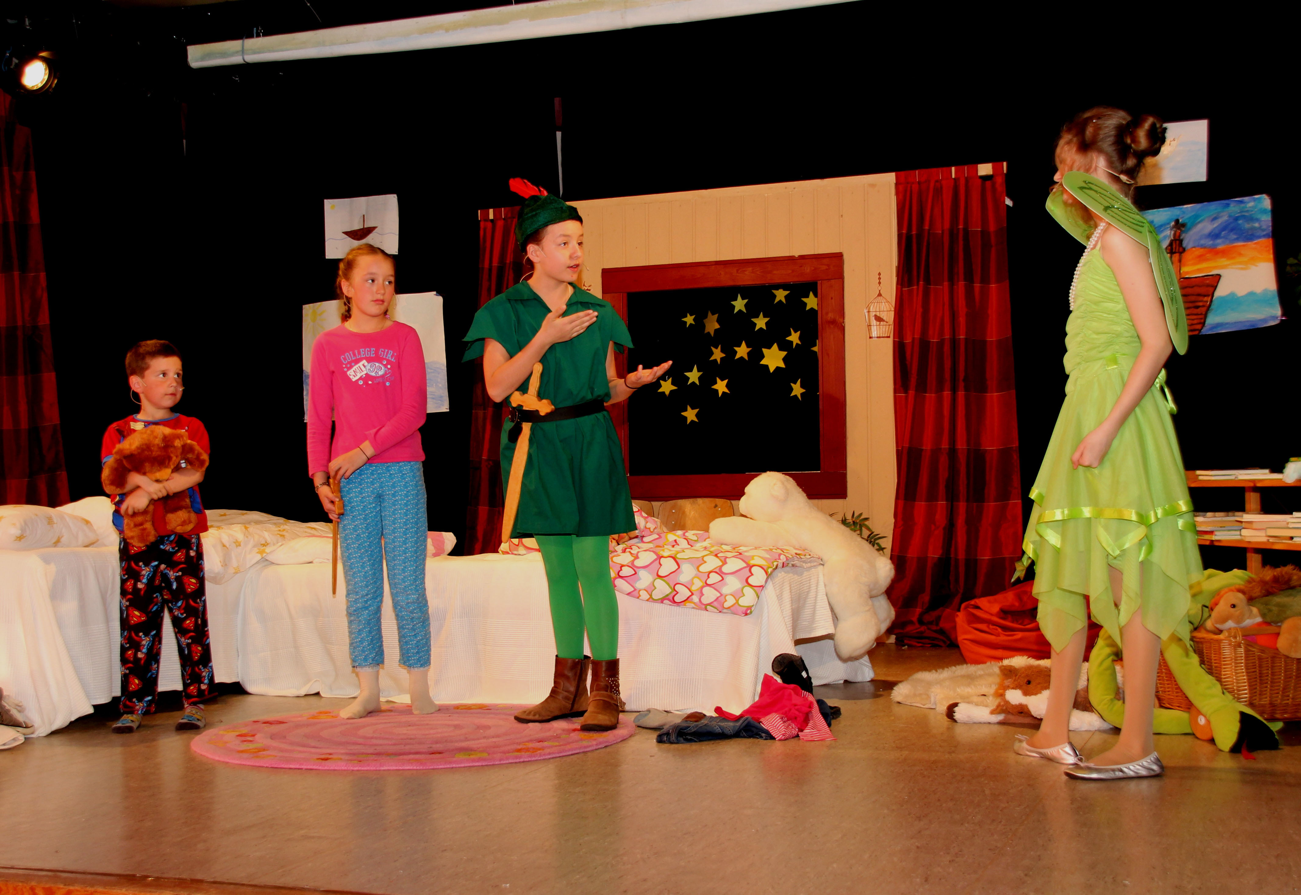 Peter Pan (Mitte) und Tinkerbell (rechts) nehmen Wendy und Michael (links) mit ins Nimmerland