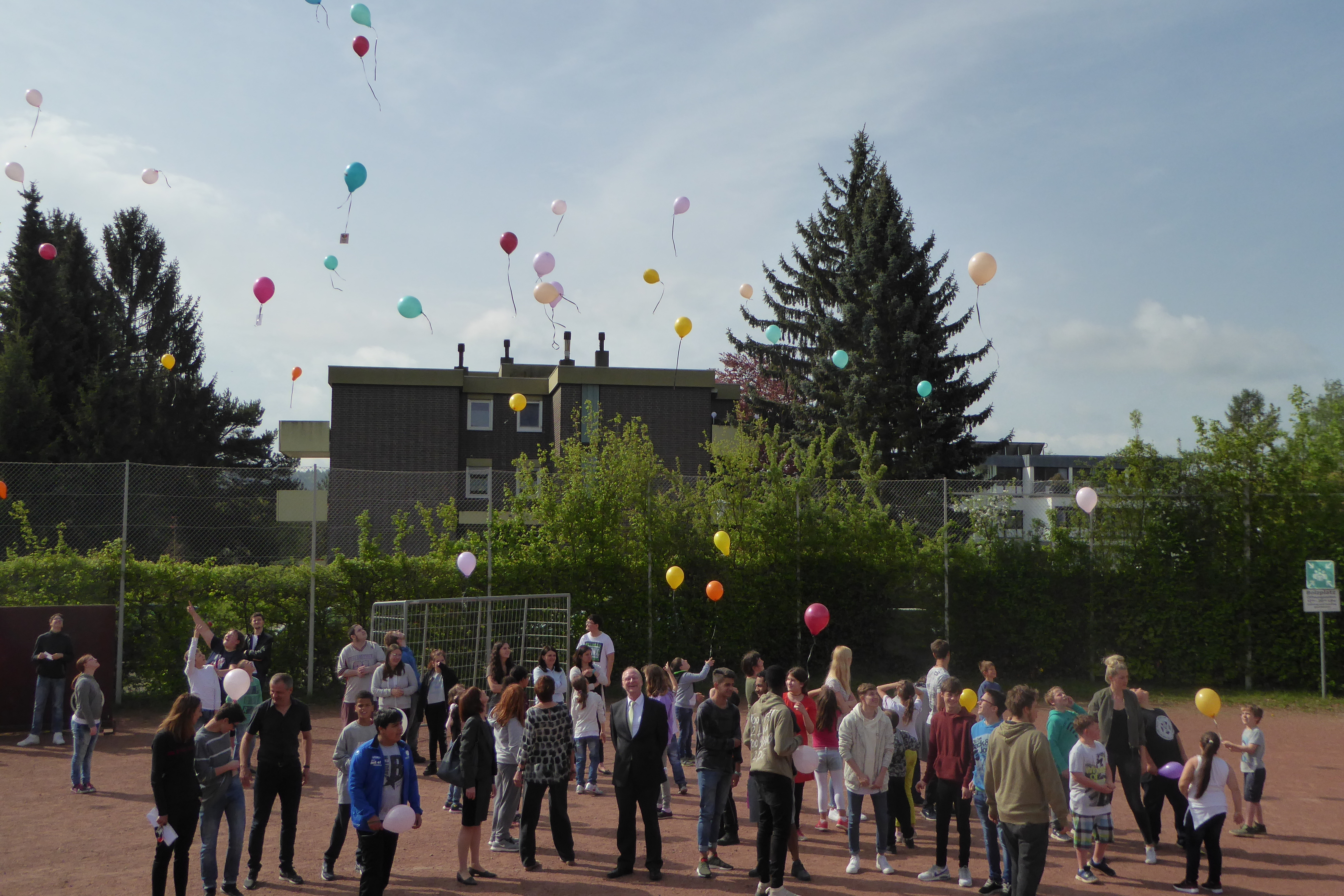 Schülerinnen und Schüler lassen Luftballons als Zeichen eines bunten Miteinanders ohne Rassismus steigen