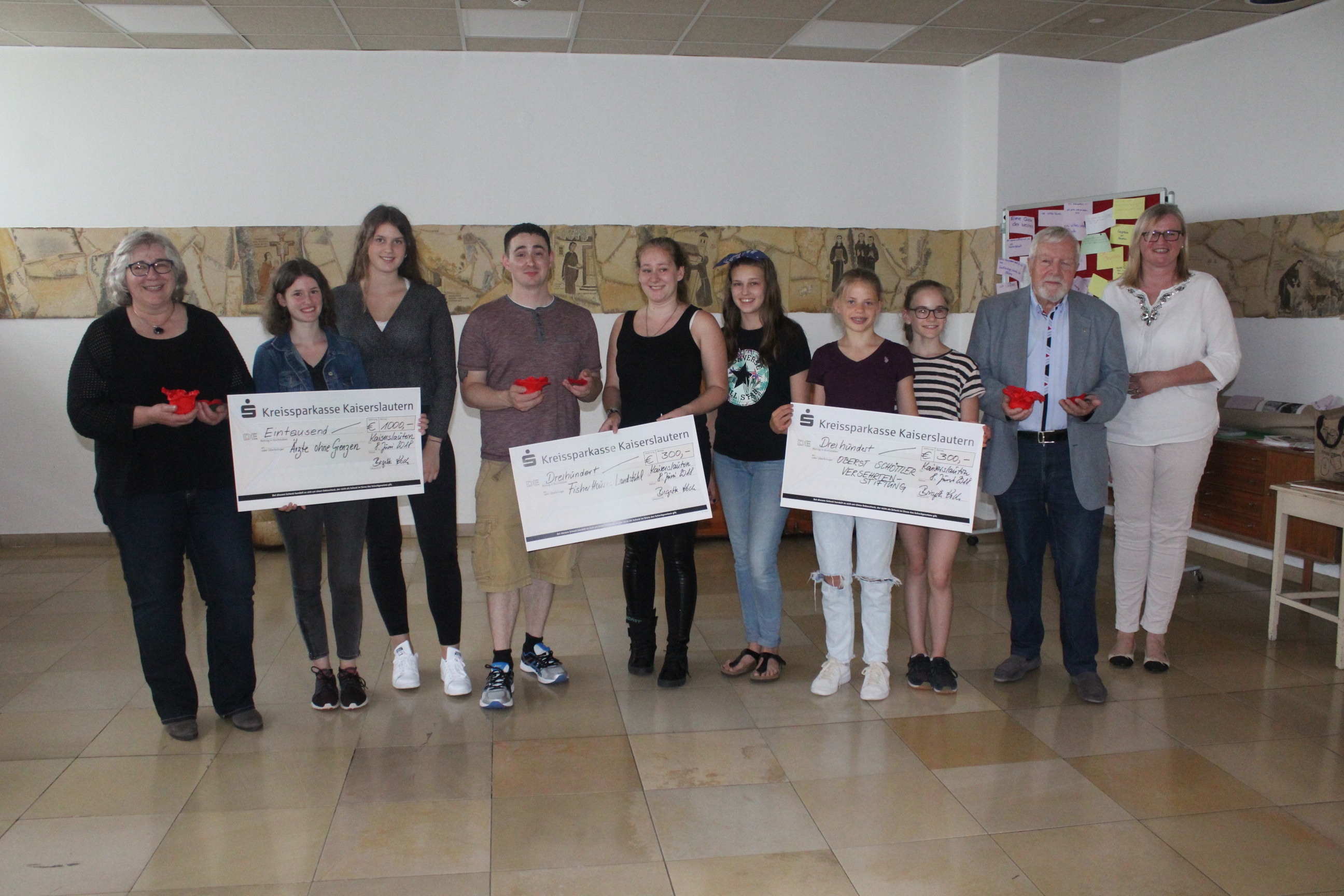 Petra Stadler (Ärzte ohne Grenzen), Lina Nauerz, Hannah Hunze, Technical Sergeant Nicholas Vidal (Fisher House Foundation), Chantal Saliger, Jule Hauck, Fleur van der Meijden, Lina Blauth, Oberst Dr. Horst Schöttler (Oberst Schöttler Versehrtenstiftung), Birgitta Koch (Projektleiterin Poppy Day) (von links) bei der Scheckübergabe