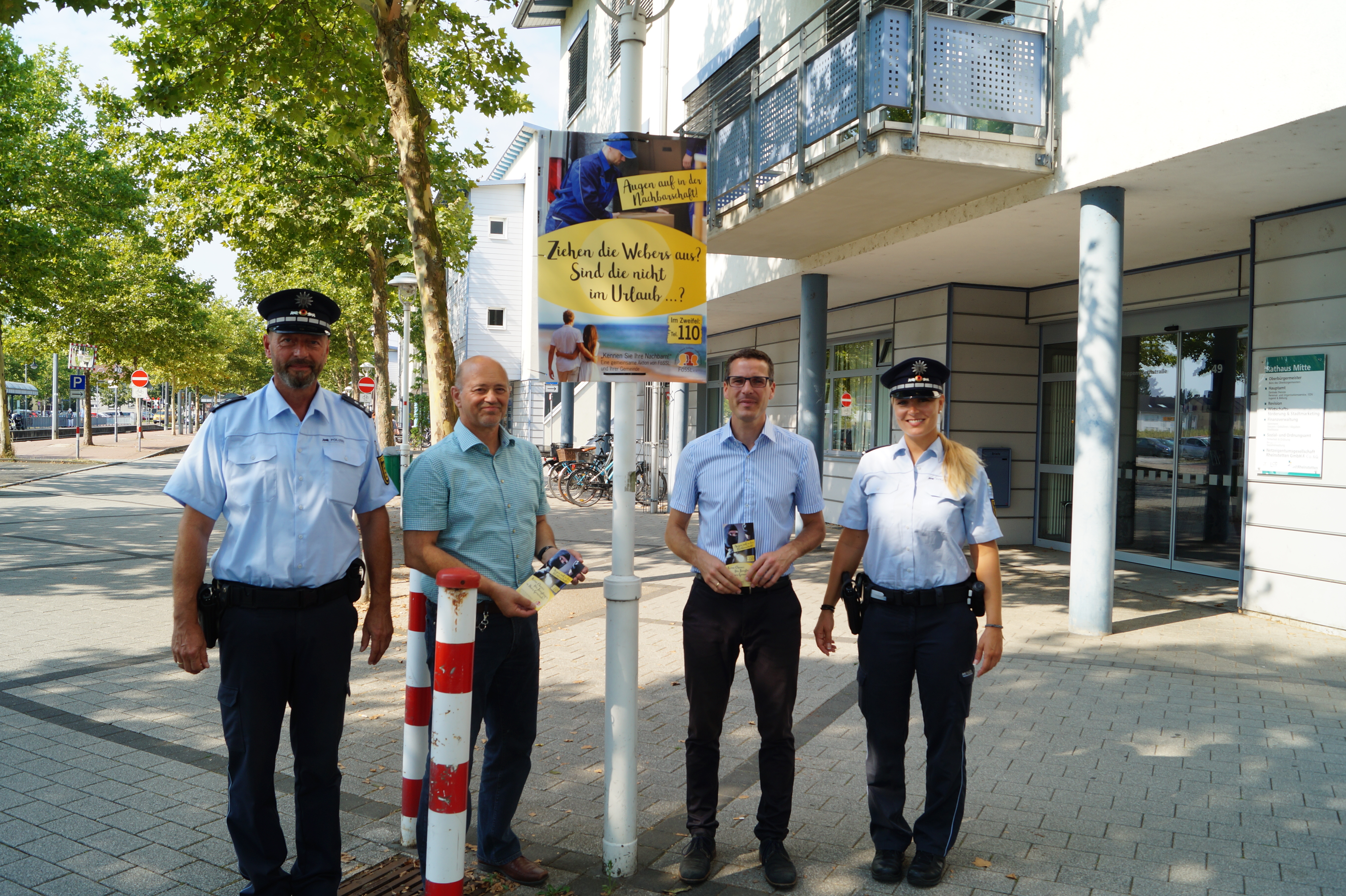 Jörg Hofmann, Ronald Daum, Sebastian Schrempp und Susann Benter (v.l.) hängen das erste Plakat am Rathaus Mitte gemeinsam auf.