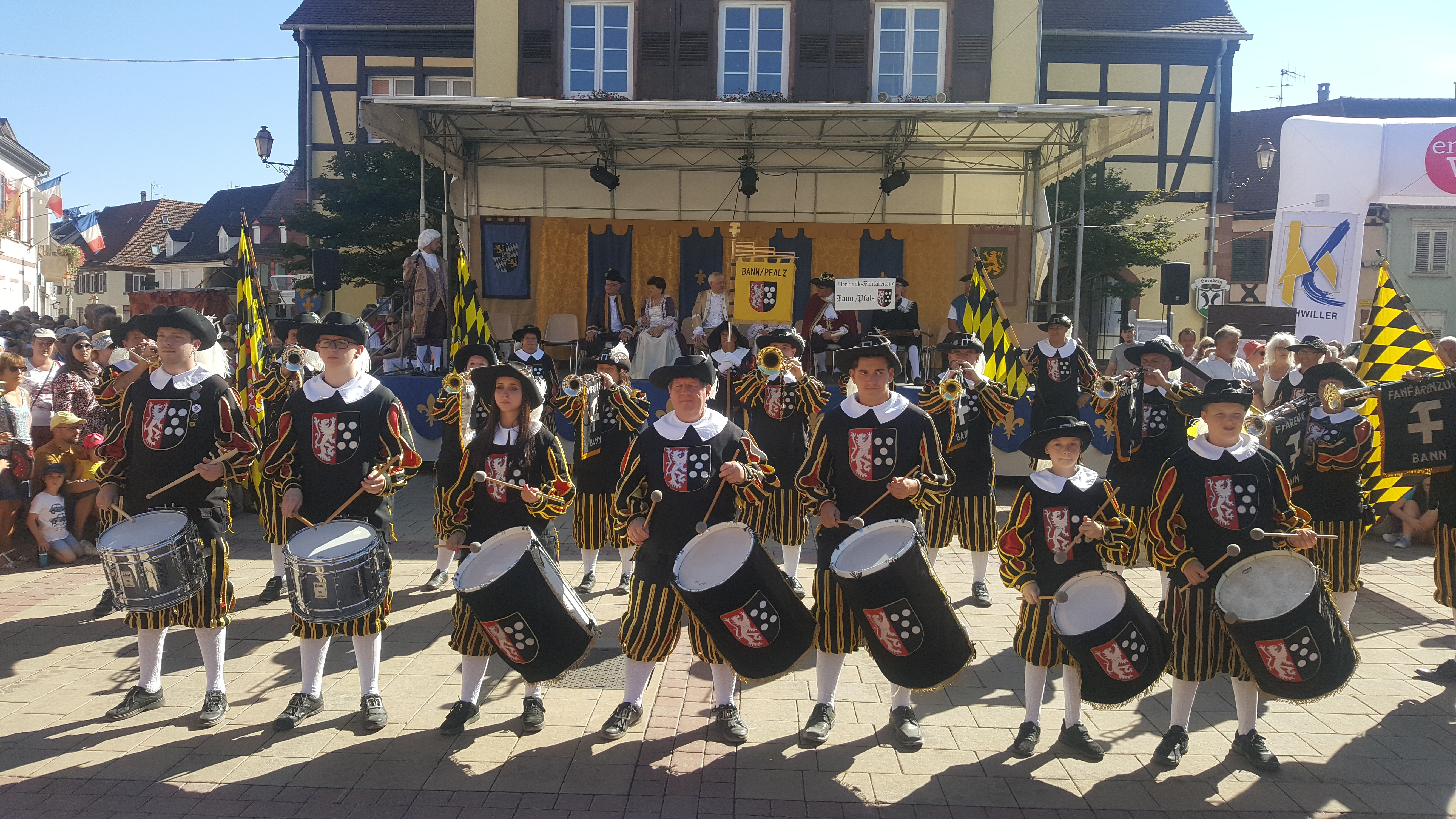 Ein Teil des Fanfarenzuges Bann beim Trommel- und Fanfarenspiel vor dem alten Rathaus in Bischwiller. Die Schwing- und Wurffahnen waren quer über den Festplatz verteilt.