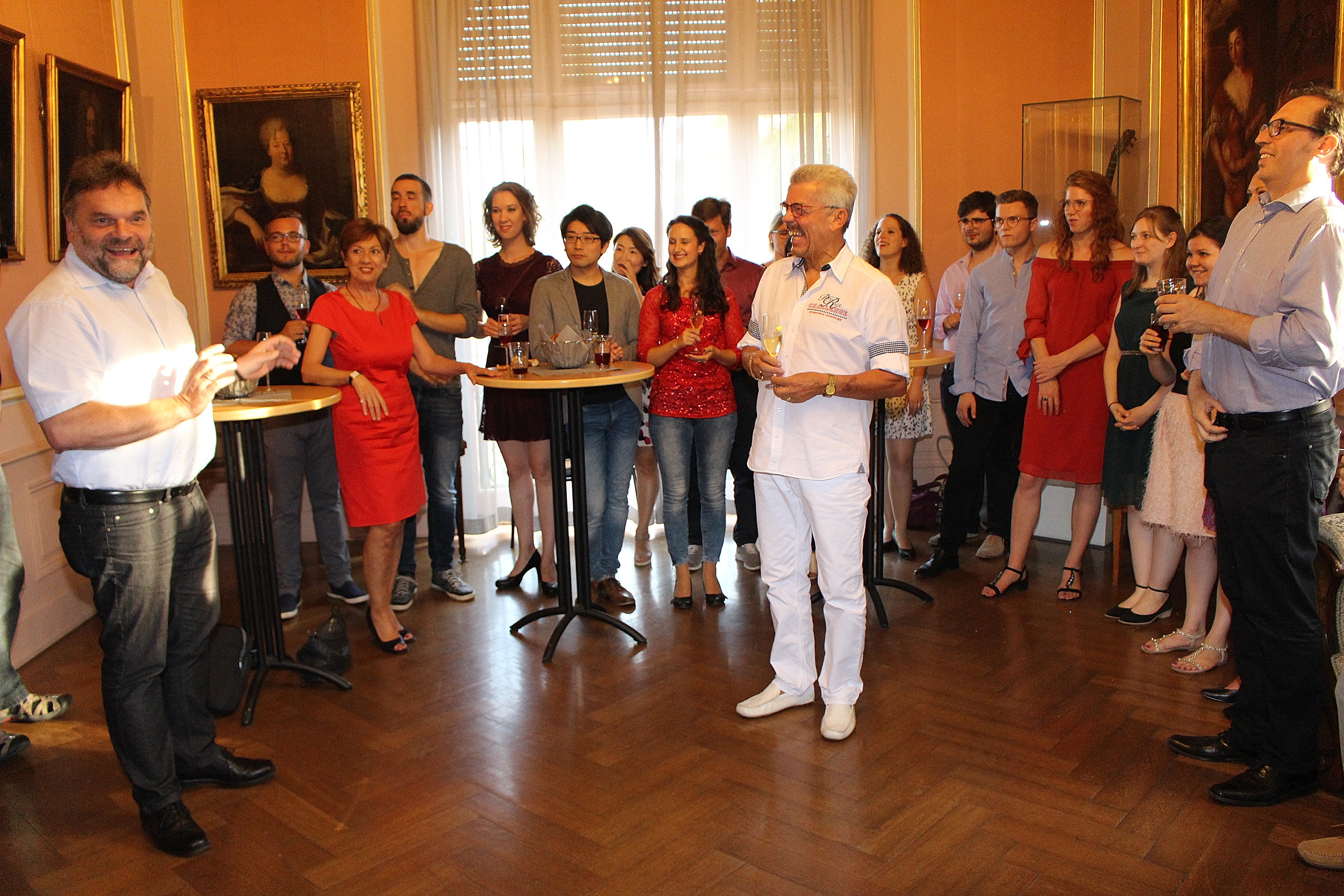 Kulturdezernent Ingo Röthlingshöfer (links) und Hansjürgen Hoffmann, 1. Vorsitzender des Fördervereins Meisterkurs für Gesang (Mitte) begrüßen die Kursteilnehmer im Salon der Villa Böhm.