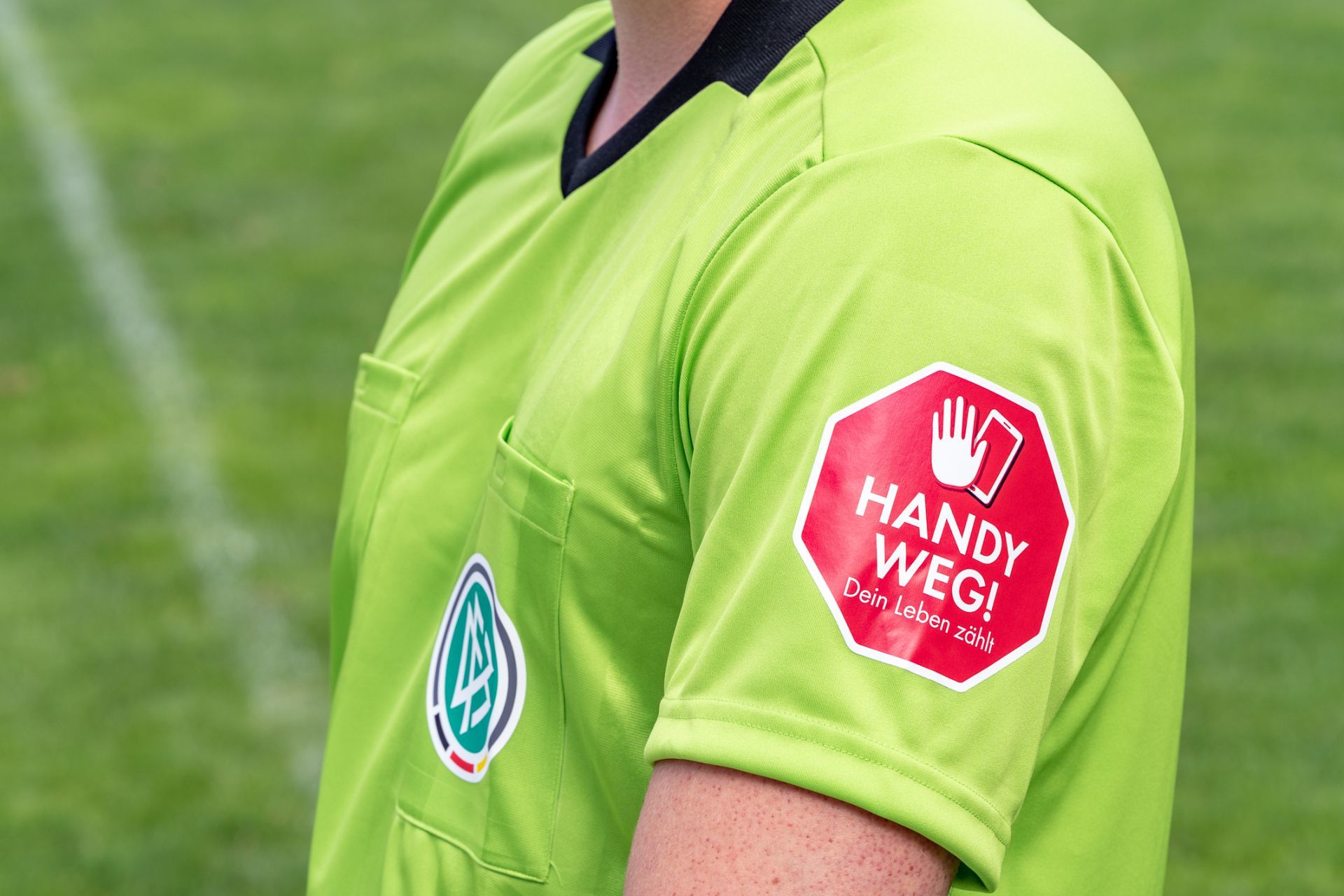 Wichtiger Hinweis: Auf den Ärmeln der Schiedsrichter und seiner Assistenten prangt beim Bundesliga-Auftaktspiel „Handy weg – dein Leben zählt“.