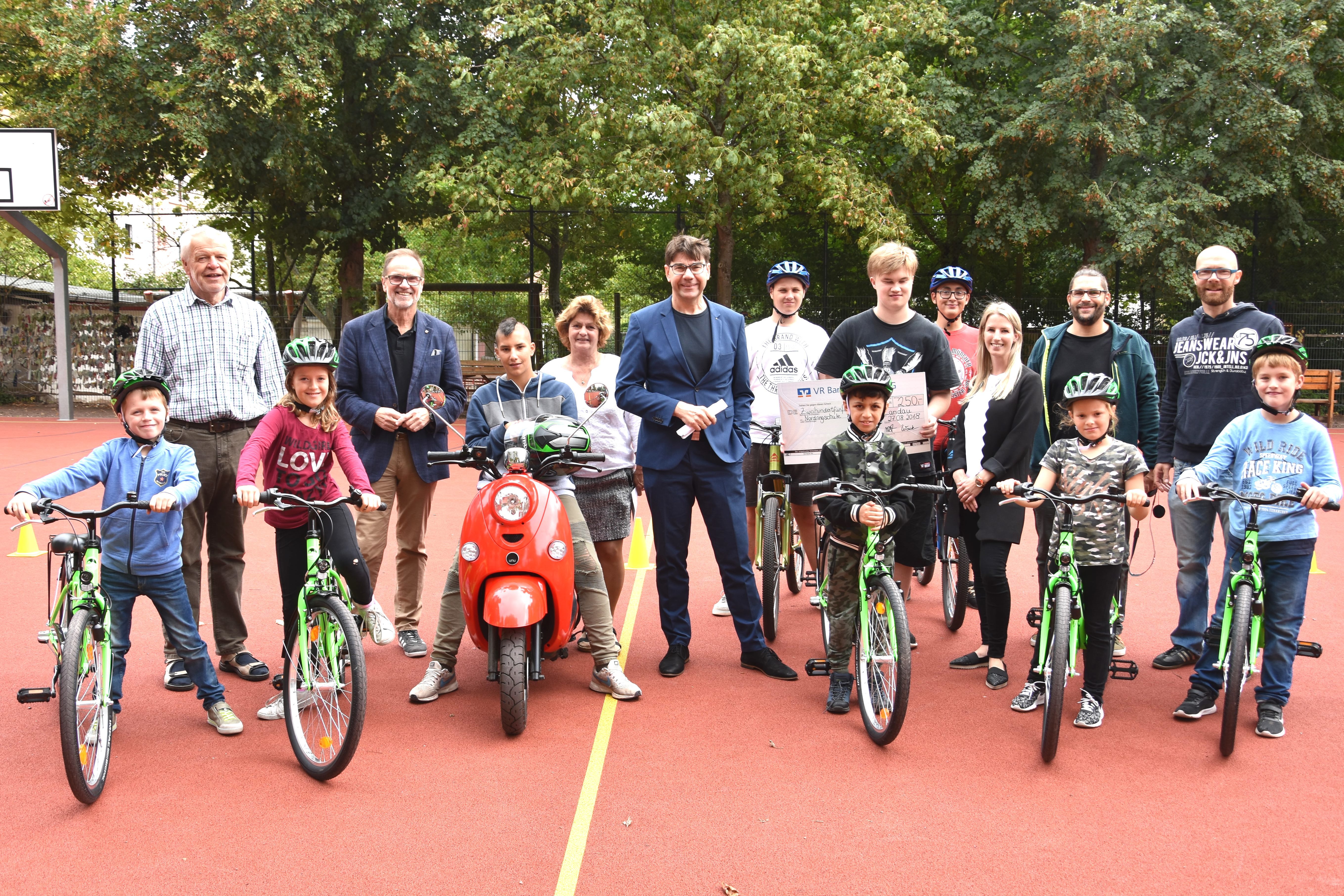 Oberbürgermeister Thomas Hirsch (M.), Landtagsabgeordneter Wolfgang Schwarz (2.v.l.) und Schulleiterin Angelika Bühler (3.v.l.) gemeinsam mit Lehrern und Mitgliedern des Mofa-Kurses und der Fahrradwerkstatt bei der kleinen Feierstunde auf dem Schulhof der Nordringschule.