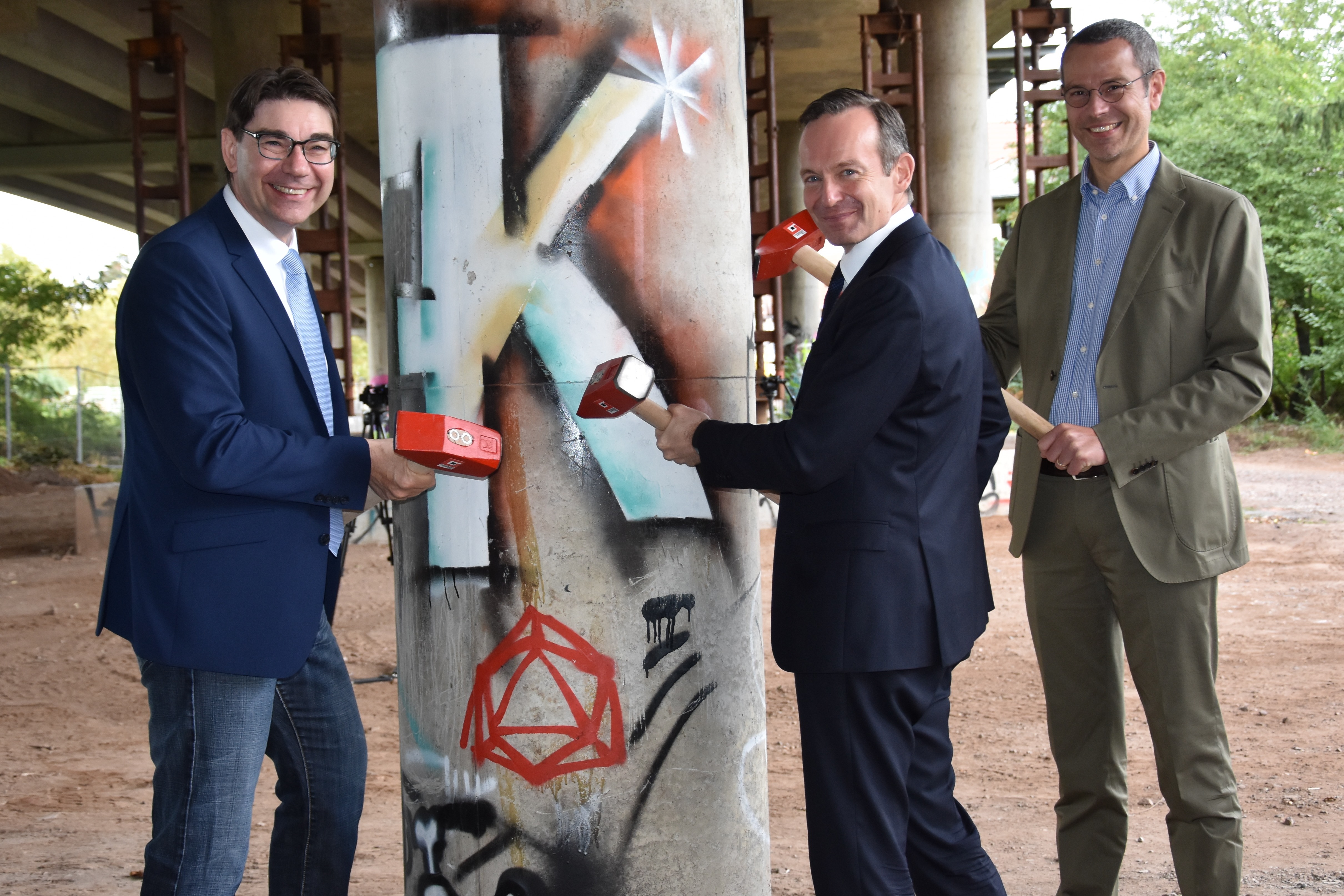 Oberbürgermeister Thomas Hirsch, Verkehrsminister Dr. Volker Wissing und Bürgermeister Dr. Maximilian Ingenthron (v.l.n.r.) beim symbolischen Hammerschlag zu Beginn des Abrisses und Neubaus der nördlichen Horstbrücke.