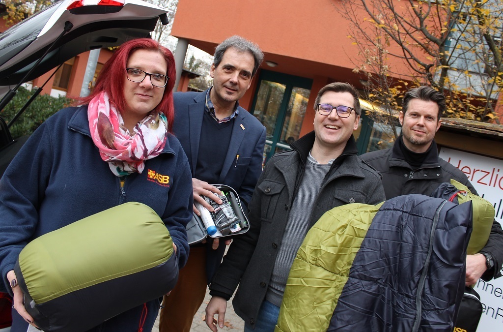 Sebastian Benz (mit Brille) und Jens Gattringer (r.) geben die Schlafsäcke nun im Julius Itzel Haus an Bedürftige weiter. Dr. Andreas Bröker, ASB-Regionalgeschäftsführer, hat eines der Hygiene-Sets in der Hand. Karin Kremer von der ASB-Sozialstation Bruchsal leitete die Spende ein.