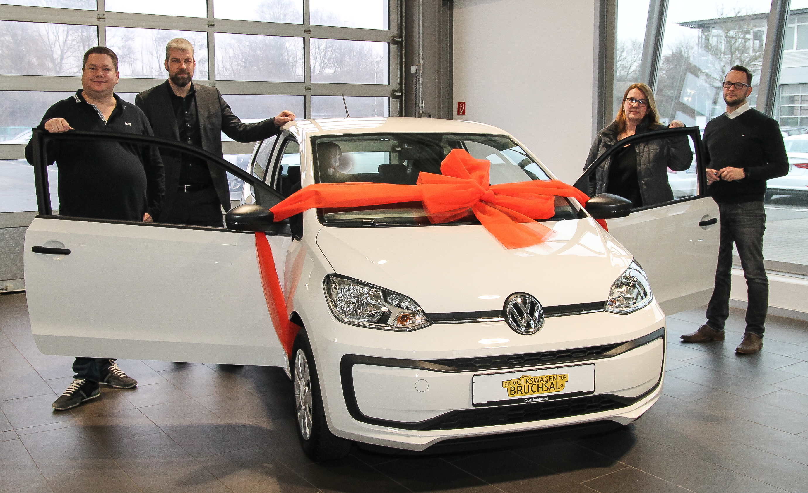 Sven Wipper (B3), Andy Kocijan (Niederlassungsleiter Graf Hardenberg), Gewinnerin Monika Adam und Timo Dürr (Graf Hardenberg) mit dem "Volkswagen für Bruchsal" der zu Weihnachten verlost wurde