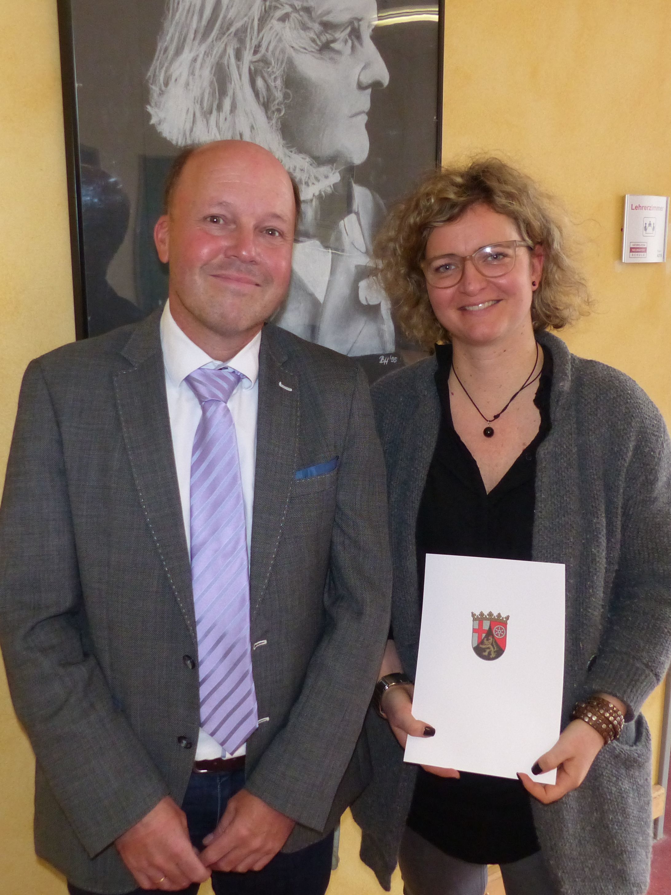 Schulleiter Jörg Oeynhausen überreicht die Urkunde zur Beförderung an Anna Kehr