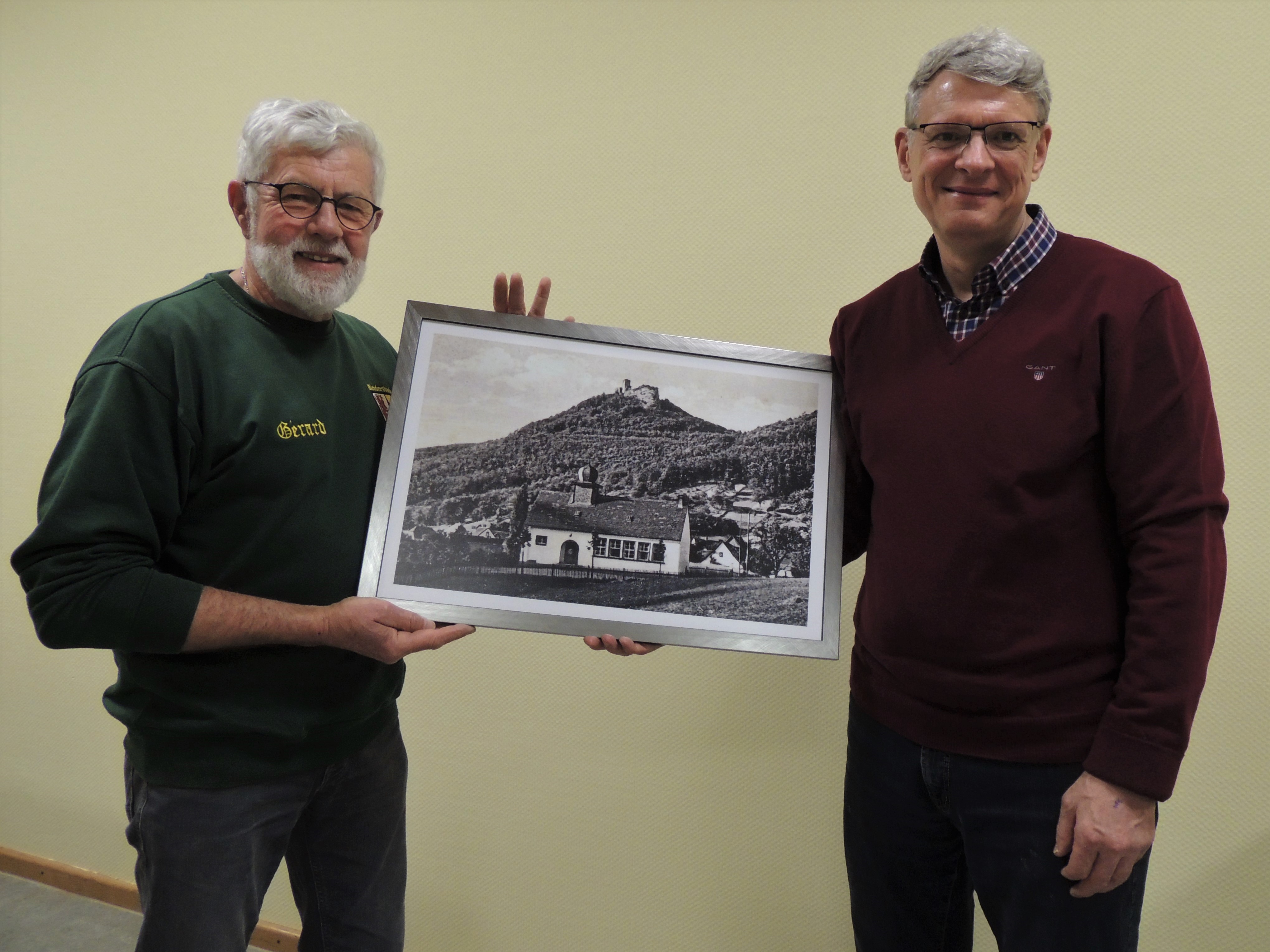 Thomas Wollenweber überreicht dem Vorsitzenden des Brauchtumvereins, Gérard Salmon, das gerahmte Siegerfoto.