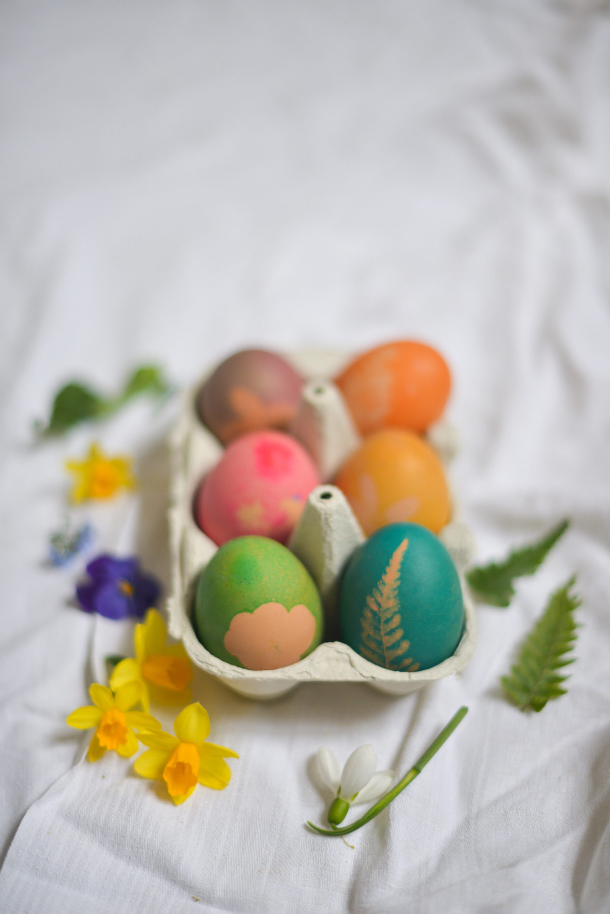 Gefärbte Eier und Blüten bringen Frühlingsstimmung auf den Tisch.