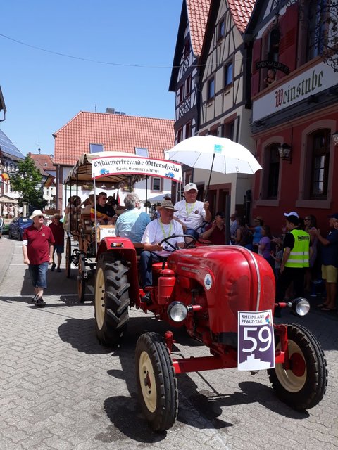 Ein historischer Gesellschaftswagen wird von einem roten Porsche-Schlepper der Oldtimerfreunde Ottersheim gezogen. | Foto: ps