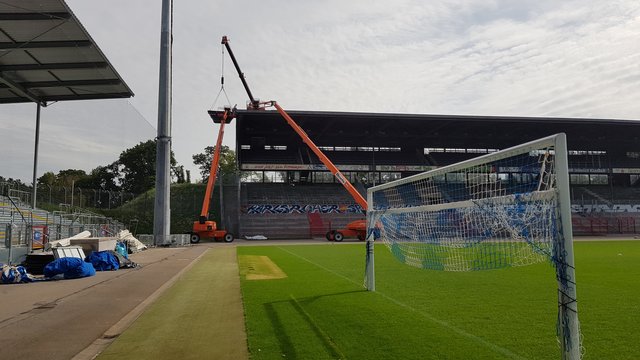 Seit Dienstag, 6. August 2019, läuft der Abbau/Abriss der Gegentribüne des Wildparkstadions in Karlsruhe. Es ist ein aufwändiges Verfahren: Mehrere Kräne stehen an der Tribüne, einer reicht sogar direkt darüber, Arbeiter in Schutzkleidung (Asbest) zerlegen auf dem Dach dieses vor Ort zunächst Platte für Platte. Ein Container wird mit einem Kran an die Arbeitsstelle hochgehoben, dort werden die Platten dann abgelegt. Ist der Container voll, geht's damit wieder runter, dann werden die Platten umgeladen, besonders verpackt - und dann geht der Sondermüll zur Deponie.  | Foto: jnb