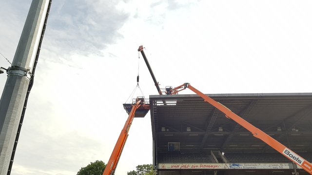 Ein Stück fehlt schon!
Seit Dienstag, 6. August 2019, läuft der Abbau/Abriss der Gegentribüne des Wildparkstadions in Karlsruhe. Es ist ein aufwändiges Verfahren: Mehrere Kräne stehen an der Tribüne, einer reicht sogar direkt darüber, Arbeiter in Schutzkleidung (Asbest) zerlegen auf dem Dach dieses vor Ort zunächst Platte für Platte. Ein Container wird mit einem Kran an die Arbeitsstelle hochgehoben, dort werden die Platten dann abgelegt. Ist der Container voll, geht's damit wieder runter, dann werden die Platten umgeladen, besonders verpackt - und dann geht der Sondermüll zur Deponie.  | Foto: jnb
