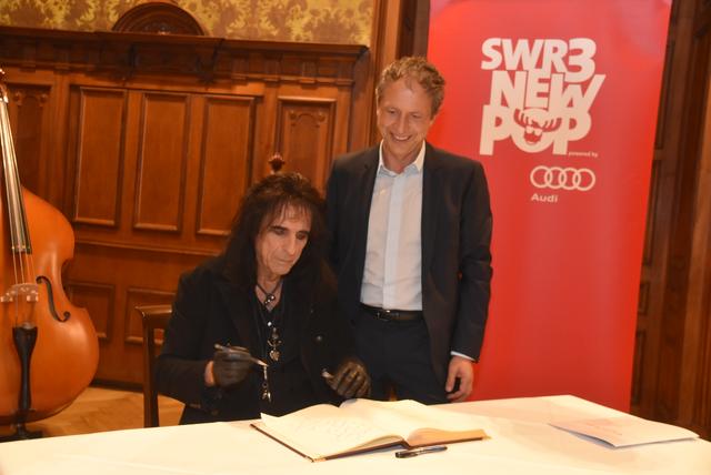 In typischer Kleidung und Outfit trägt sich der US-Rockmusiker Alice Cooper in das Goldene Buch Baden-Badens ein. Rechts Bürgermeister Roland Kaiser.  | Foto: Roland Seiter