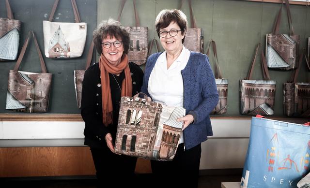 Monika Hoff (links), die Leiterin der Schulmanufaktur, übergibt ein erstes Exemplar der Domtasche an Bürgermeisterin Monika Kabs, die vielleicht ihre alte Speyer-Tasche (rechts im Bild) ersetzen kann.
