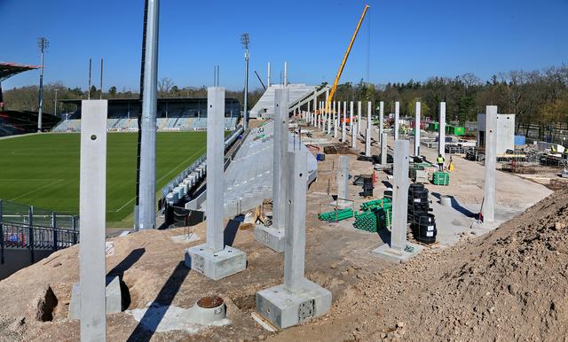 Steht: Viele der die Last des Stadiondaches tragenden Pylonen stehen bereits – im Hintergrund werden mit einem Kran bereits die Fertigteile eingehoben, die die Sitzplatzunterkonstruktion bilden. | Foto: Roland Fränkle/EIBS