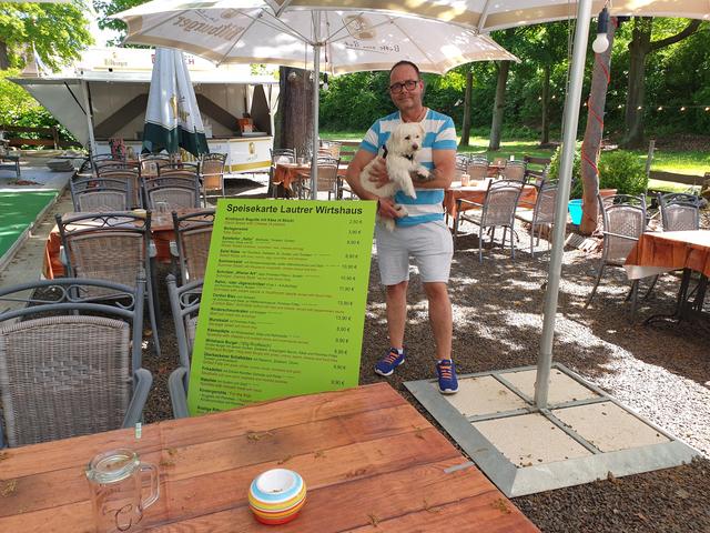 Uwe Graf mit Hund Oscar und Speisekarte im auf Abstand getrimmten Biergarten des Lautrer Wirtshaus | Foto: Ralf Vester