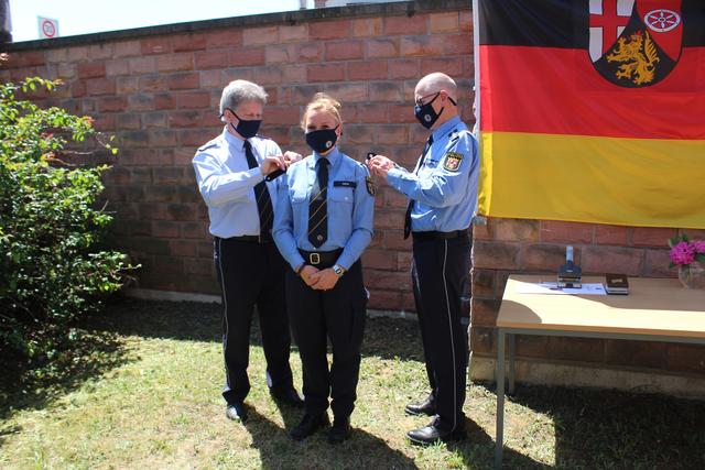 Arno Heeling (links) und Peter Natter (rechts) wechseln traditionsgemäß die Schulterstücke bei der frisch gebackenen Polizeioberkommissarin Sabrina Fath... | Foto: pol