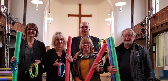 Mehr Schwimmkompetenz für Kinder: Beim KinderVesperkirche-Pressegespräch gab es symbolisch „Schwimmnudeln“ von Dekan Ralph Hartmann, Projektleiterin Ruth Würfel (Mitte) und Udo Scholz (Adler helfen Menschen e.V.) für die Schulrektorinnen Sylvia Kessler und Monika Walz-Kurz (links).  | Foto: de Vos