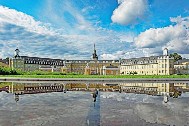Das Schloss Karlsruhe spiegelt sich in einem der Wasserbecken auf dem Schlossplatz (aufgenommen im Juli).
