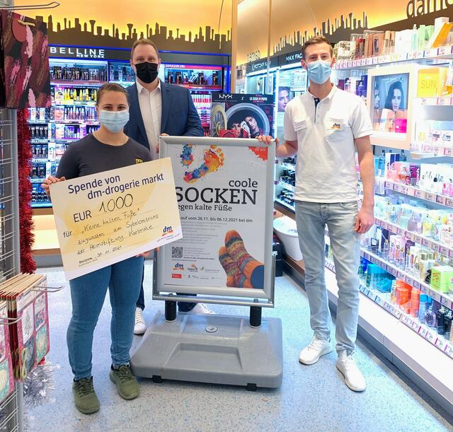 Philipp Herz (Gebietsverantwortlicher dm-drogerie markt, Mitte) und Waldemar Wischnewski (Filialleiter dm-drogerie markt Raiherwiesenstrasse, rechts) überreichen Sabine Kusterer einen Scheck über den aufgerundeten Umsatz.