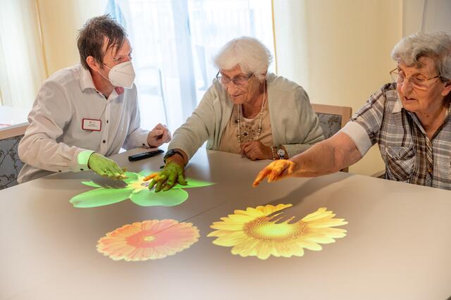 Ein Beamer projiziert Spiele auf einen Tisch; diese regen mit Farben, Klängen und Bewegung Sinne und Motorik an | Foto: Dietmar Hopp Stiftung/Thomas Neu