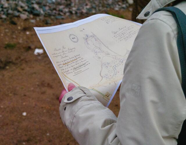 Eine Vertreterin des Festungsbauvereins Landau sieht sich eine alte Karte an und vergleicht sie mit den Ausgrabungen vor Ort | Foto: Kim Rileit