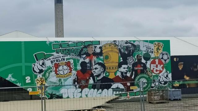 Das Pokalfinale wirft seinen Schatten voraus: In Berlin sind die Spieler der Roten Teufel, Ragnar Ache, Jan Evledi und Tymoteusz Puchacz als Graffiti an der Wand neben Florian Wirtz und Co zu sehen | Foto: Katharina Schmitt