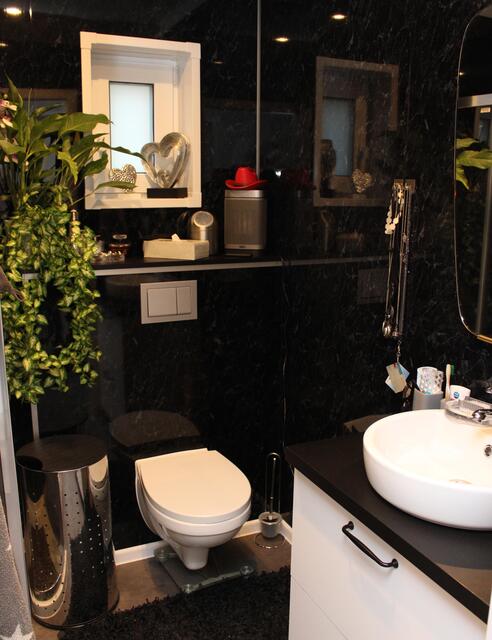 In Schwarz gehalten: Das Bad mit Waschbecken und Toilette, die Dusche verbirgt sich links | Foto: Monika Klein