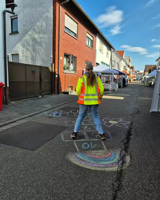 Hier springt eine Besucherin, fröhlich und energiegeladen über die Straße das Hüpfspiel. Sie hat ein Lächeln im Gesicht und ist begeistert von dieser Idee. | Foto: Angelika Schreiweis-Brezinova