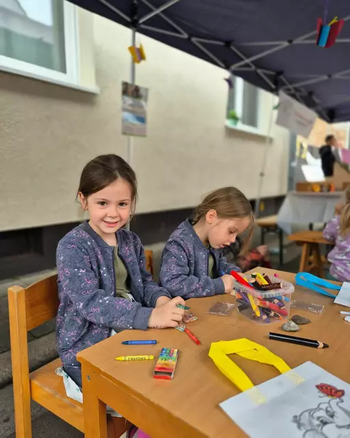 Mehrere Kinder zu besuch, am bunten Infostand des Vereins Pro Kindertagespflege Vorderpfalz. Einige Kinder sitzen an den Tischen und malen oder basteln, während andere neugierig den Stand erkunden. Die Kinder wirken begeistert und konzentriert bei ihren kreativen Aktivitäten. | Foto: Angelika Schreiweis-Brezinova