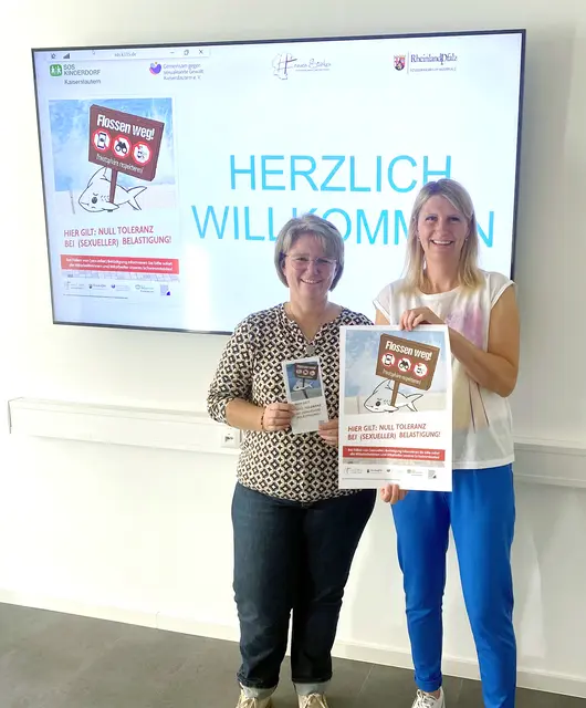 Zeigen Plakate und Flyer des "Flossen weg!"-Präventionsprojektes: Petra Brenk (links), Kreisjugendpflegerin des Landkreises Kaiserslautern, und Dorothee Müller, Gleichstellungsbeauftragte des Landkreises Kaiserslautern | Foto: Kreisverwaltung KL/gratis