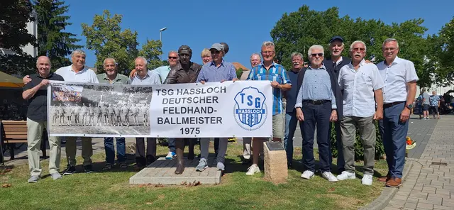 Stolz präsentiert die Mannschaft von 1975 das Banner zur Erinnerung an die Meisterschaft am bronzenen Feldhandballer am Jahnplatz; rechts: Sportbund Pfalz-Präsident Rudolf Storck. | Foto: Kaufmann