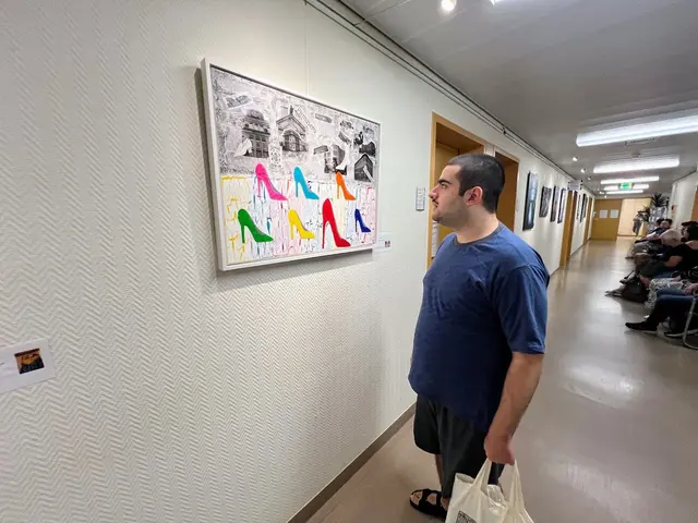 Ahmad beobachtet mit großem Interesse das Kunstwerk der Künstlerin Bärbel Kettenring, das die Bedeutung der Schuhindustrie in Pirmasens veranschaulicht. Ein farbenfrohes Werk, das Pirmasens in seiner Geschichte und Gegenwart als Schuhstadt zeigt: Im Zentrum ein Reißverschluss, der eine Hand freilegt – Symbol für Öffnung und Bewegung. Umgeben von bunten Schuhen, Beinen und Farbspritzern, verbindet das Bild Tradition und Moderne, Mode und Identität.
Werk: Bärbel Kettenring – Foto: Zeinhom Haggag
— hier: Städtisches Krankenhaus Pirmasens. | Foto: Werk: Bärbel Kettenring – Foto: Zeinhom Haggag