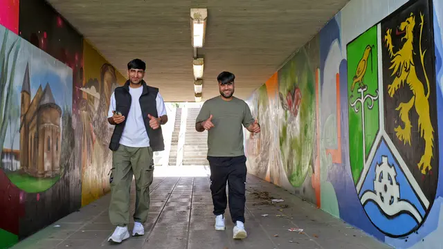 Die neue Street-Art-Unterführung am Bahnhof Bruchmühlbach-Miesau wird bereits rege von den Zugfahrern genutzt, wie hier von Mohammad Farooq Hotaki (rechts) und Fahim Masoudi.  | Foto: Erik Stegner