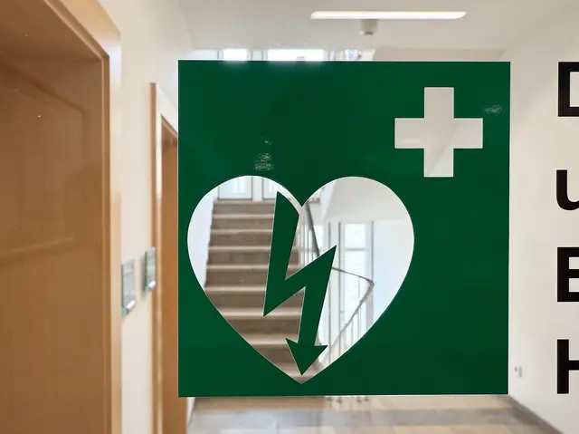 Ein Defibrillator-Symbol weist im Reichswaldgymnasium den Weg: Beim neuen Pilotprojekt sollen Schülerinnen und Schüler lernen, im Notfall Leben zu retten. | Foto: Landkreis Kaiserslautern