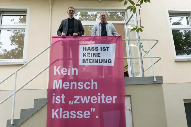 Die Kirchen machen sich stark für Demokratie und Menschenwürde: Die Ludwigshafener Dekane Dominik Geiger (katholisch, links) und Paul Metzger (evangelisch) mit einer Fahne, von denen 30 am Wochenende in der Stadt gehisst werden. | Foto: Prot. Dekanat LU/Wagner