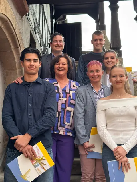 Das Foto zeigt von links nach rechts oben den 1. Beigeordneten Patrick Poss (im Sakko) und Martin Schoppel; vorne stehen von links nach rechts:  Kartfahrer Devin Leon Ucar, Bürgermeisterin Ilona Volk, Stella Holczer (kariertes Hemd), Sara Djapa und Venera Stroh (weißer Pulli). 

 | Foto: Stadtverwaltung Schifferstadt