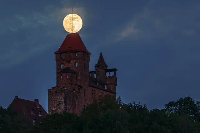 Der Vollmond über der Burg Berwartstein bei Erlenbach im Pfälzerwald: Kurz nach Mondaufgang scheint der Supermond das Turmdach zu berühren – ein faszinierender Anblick über der Südwestpfalz. | Foto: Harald Kröher