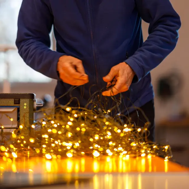 Ein Reparaturhelfer untersucht eine Lichterkette 
 | Foto: Adalbert Bukowski/gratis