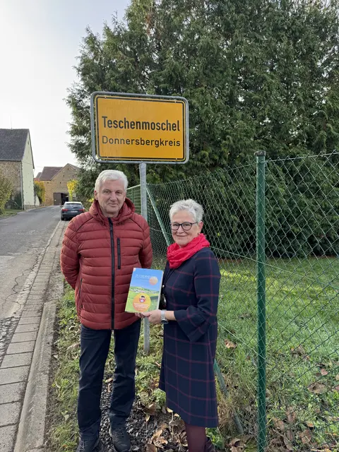 Autor Willi Schattauer und Ortsbürgermeisterin Sabine Küsters am Ortsschild von Teschenmoschel - stolz wird die neue Chronik präsentiert-  | Foto: Arno Mohr 
