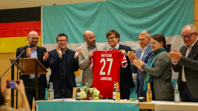 Bei der CDU-Mitgliederversammlung in Bann erhielt Christopher Bretscher nicht nur 131 Stimmen und die offizielle Nominierung zum Verbandsbürgermeister-Kandidaten – Stadtbürgermeister Mattia De Fazio überreichte ihm symbolisch ein FCK-Trikot mit der Nummer 27. | Foto: Erik Stegner