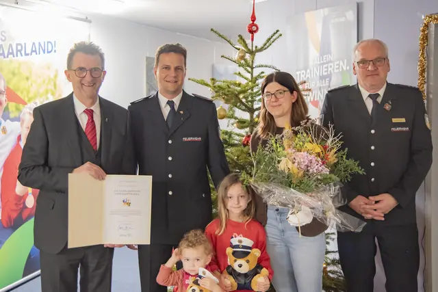 (v.l.n.r.): Innenminister Reinhold Jost; Johannes Bohr mit seiner Familie; stellvertretender Wehrführer der Feuerwehr Saarlouis, Jörg Schmitz | Foto: MIBS/F. Roggenland