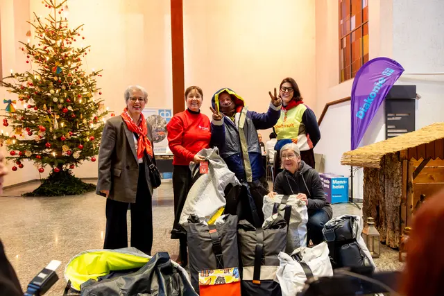 Spendenübergabe der Sheltersuits an einen Gast (Mitte) aus der Vesperkirche, (v.l.n.r.): Isabel Prinzessin zu Löwenstein (links, Vorsitzende JHG Kurpfalz), Lisa Wiebalck (2. von links, JHG Kurpfalz), Carina Eijsink (Sheltersuit Foundation, rechts stehend) mit Pfarrerin Anne Ressel | Foto: Till Kretner