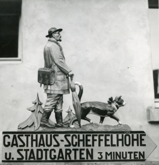 Dieser historische Wegweiser führte vor 1945 Besucher vom Schloss Bruchsal hoch in die neben dem Stadtgarten liegende Gaststätte „Scheffelhöhe“. Es zeigt Scheffel und den Kater Hidigeigei | Foto: Stadtarchiv Bruchsal