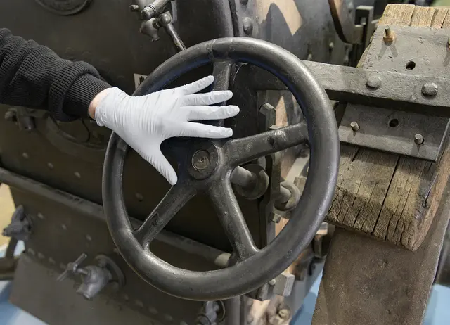 Eine Hand, die einen Handschuh trägt, ertastet eine historische Landmaschine im Technoseum | Foto: Technoseum/Klaus Luginsland