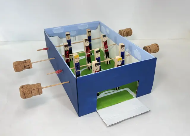 Ein aus einem Schuhkarton hergestellter Tischkicker mit Spielerfiguren aus bemalten Wäscheklammern | Foto: Historisches Museum der Pfalz/Hannah Rothaug 