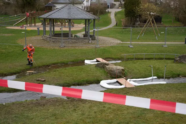 Ein Arbeiter pumpt mit Hilfe einer Ölsperre das durch Diesel verunreinigte Wasser aus dem Bach ab.  | Foto: dpa