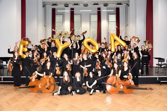 Was hier wie ein einziges großes Orchester wirkt, ist das Ergebnis von zehn intensiven Tagen gemeinsamer Arbeit. Seit seiner Gründung im Jahr 2019 vereinen sich jährlich über 80 hoch talentierte junge Musiker:innen aus ganz Europa im Rahmen der European Youth Orchestra Academy (EYOA) für zehn Tage in Mannheim, wachsen musikalisch wie menschlich zusammen und entwickeln in kürzester Zeit einen gemeinsamen Klang. Die EYOA ist dabei mehr als ein Orchesterprojekt: Sie ist ein internationales Bootcamp für junge Talente, das sich 2026 – im siebten Jahr nach seiner Gründung – zu einem Festivalformat weiterentwickelt. Neben dem sinfonischen Kern entstehen neue Ensembleformate, Begegnungsräume und Konzerte, die Vielfalt, Offenheit und europäische Zusammenarbeit sichtbar machen. | Foto: Foto: EYOA